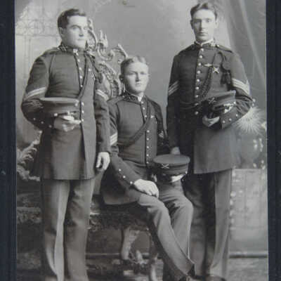 Portrait, 3 males in uniforms, 1 sitting flanked by 2 standing
