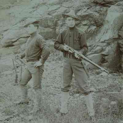 2 men in uniform, one with bugle, one with rifle