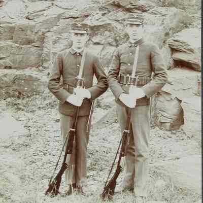 2 men in uniform with rifles standing outside