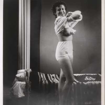 Photo - Gloria Flum written on back, B&W removing top to reveal pasties & panties "S&S Film Productions"