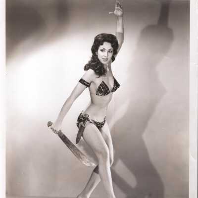 Photo - B+W Cathy Collins- In " An African Affair", in animal print 2 piece w/ knives