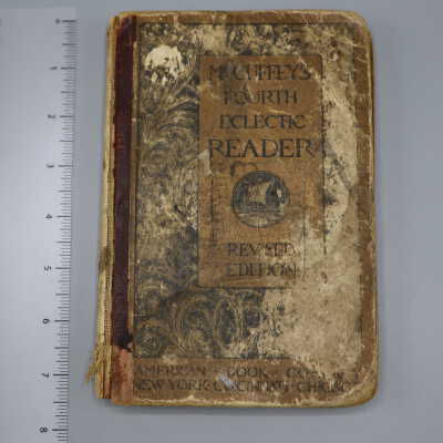 very worn hardback book with rounded corners, red spine, and tan and black design and lettering