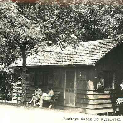 Lake Hope State Park - Buckeye Cabin #9, date unknown: Two guests relax in the shade outside of one of the many cabins located at Lake Hope State Park. Although Lake Hope lacks an overnight lodge, it has cabins for lodgers. All of Lake Hope State Park was once part of the Zaleski State Forest. Today, the Zaleski State Forest surrounds Lake Hope State Park.