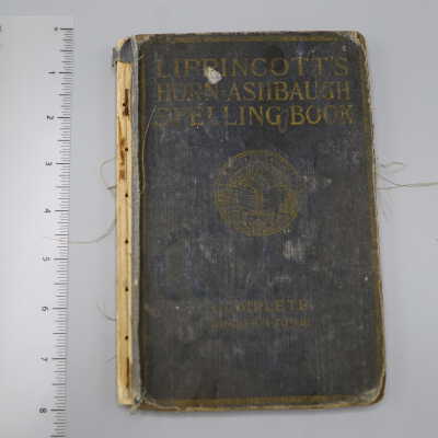 Hardback book with very worn black cover, barely legible gold embossed title and seal