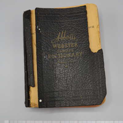 Soft cover book with black cover and faded gold lettering, tears present