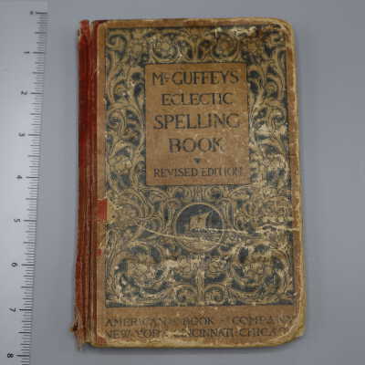 Hardback book with red spine, very worn, black and tan design on cover