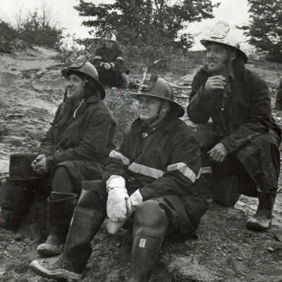 Photograph - Four firefighters sitting on the ground, Capreol fire hall fire