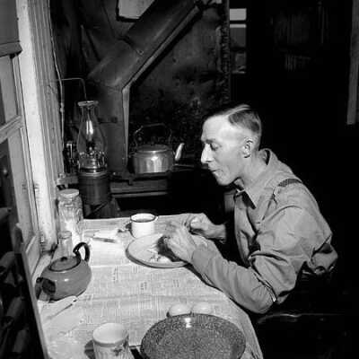 Photograph, Brakeman F.W. Gibson eats breakfast at three a.m. in a caboose with another railwayman.