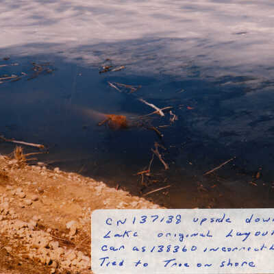 Photograph, Train Derailment, 1988, Set of 175 Pictures. "CN 137138 upside down in Lake original layout show car as 138360 incorrectly. car tied to tree on shore"