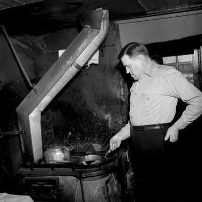 Photograph, Conductor C.E. Rose cooks himself a meal in the railway caboose.