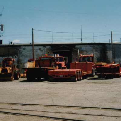 Photograph - Parked trucks and tractors in unidentified railyard