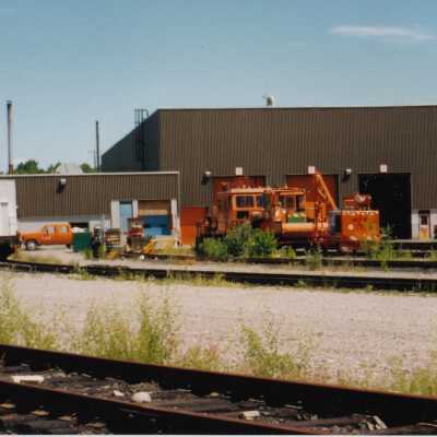 Photograph - Rail service vehicles in front of garage, unidentified railyard