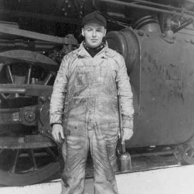 Photograph of an Unknown Canadian National Employee standing next to a Steam Engine