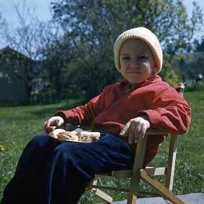 65. KJH sitting with plate of food in backyard: April 1957