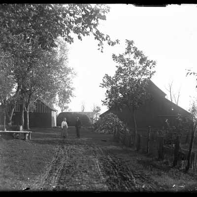 Couple standing outside farm buildings: Origsize: 4x5; Origformat: Negative