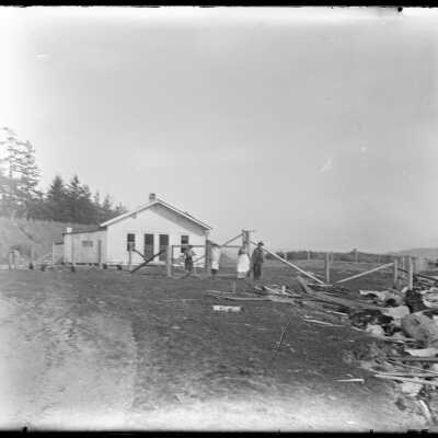 House in rear, people center, yard with lumber on right: Origsize: 4x5; Origformat: Negative