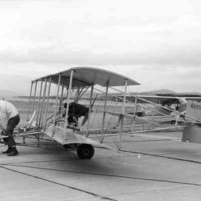 Pilot moving biplane by hand.