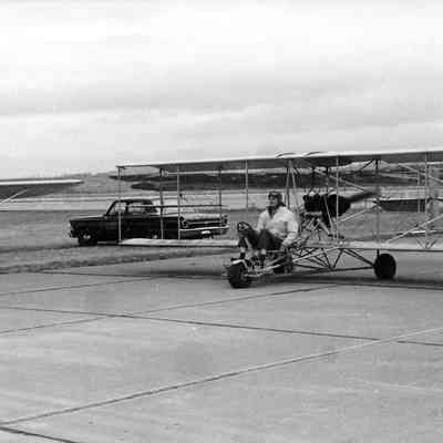 Pilot of biplane preparing for takeoff at air show.