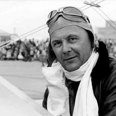Pilot dressed in leather with helmet, glasses and scarf.