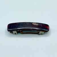 Hair barrette with dark plastic cover and metal spring clasp