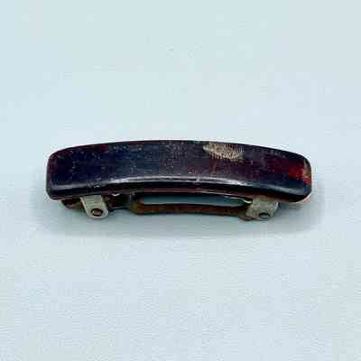 Hair barrette with dark plastic cover and metal spring clasp