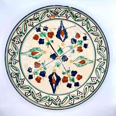 Hand-painted decorative earthenware plate, repaired