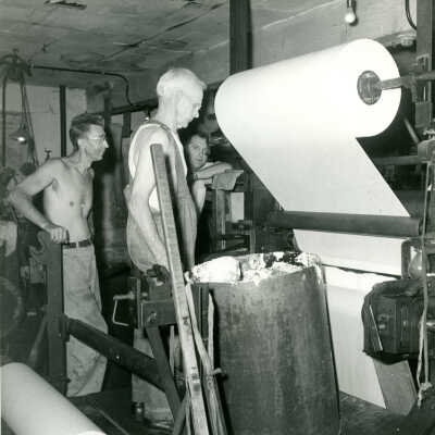 Lew Ravilious and Parker Baldwin operating the Crowell Tape Mill cloth to paper laminator machine and adding white coating