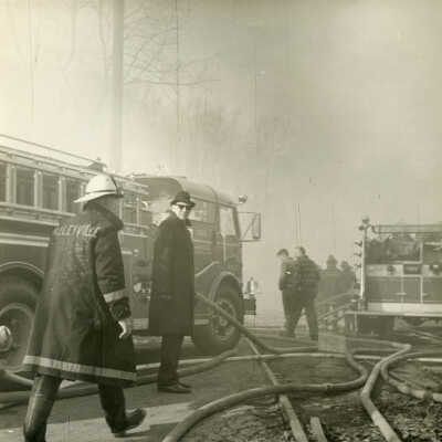 Herb Adelman with firemen on scene during fire at Crowell Tape Mill, 1964