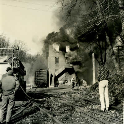 Crowell Tape Mill on fire with bystanders and fire truck, 1964