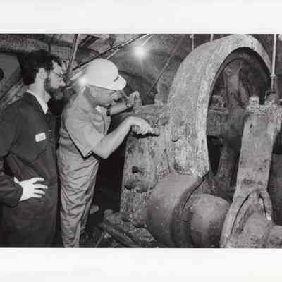 Men examine rusted compartment press photo