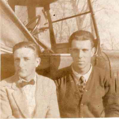 Two men sit by car