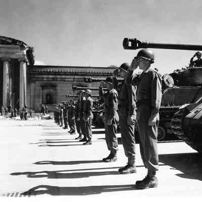 Soldiers saluting in front of tanks