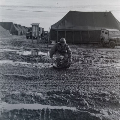 Soldier wading through mud in camp