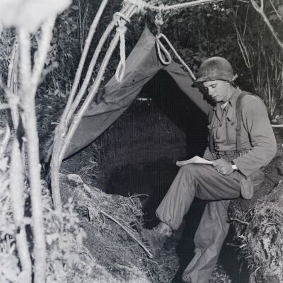 Soldier reading in front of a tent-covered command post