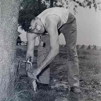 Soldier washing up at an outdoor spigot
