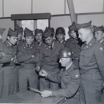 Officer signing a form among a group of Native American troops