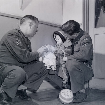 Two soldiers giving toys to a Japanese toddler