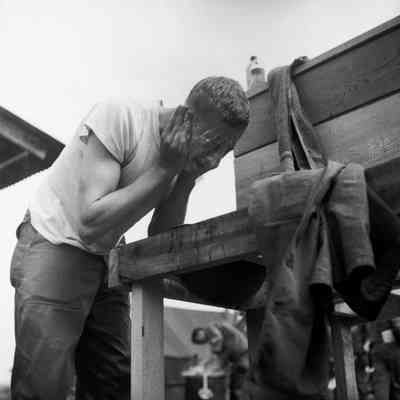 Soldier washing face in an outdoor camp wash station