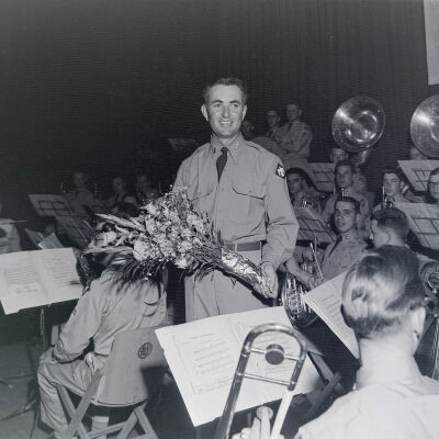 Officer with flowers in front of Army orchestra