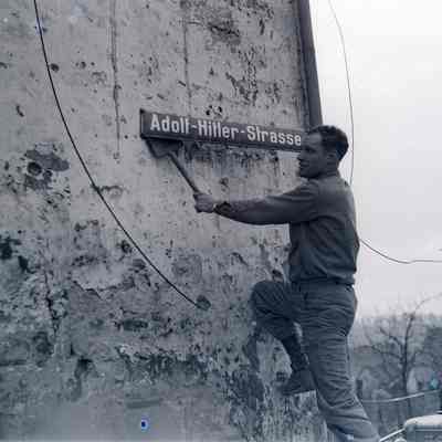 Soldier takes down a street sign named for Adolf Hitler