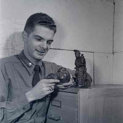 Soldier examining carved Japanese figurines