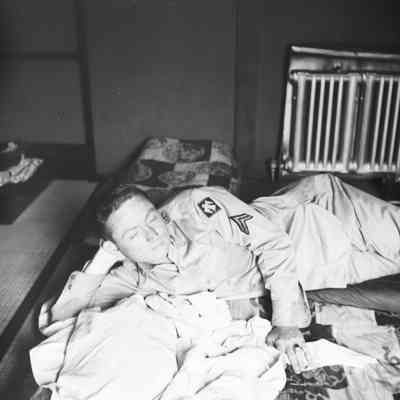 Soldier relaxing in a bed at Noboroibetsu Hotel