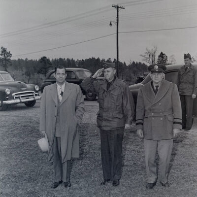 General Styron taking a salute with another general officer and a civilian