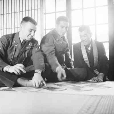 Soldiers looking at pictures with Japanese civilian