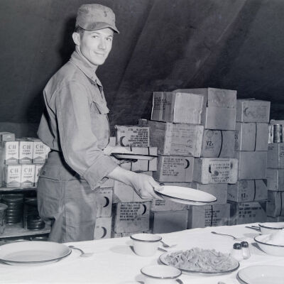 Soldier setting a table in a mess tent