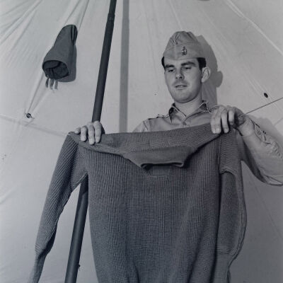 Soldier holding a sweater in a tent