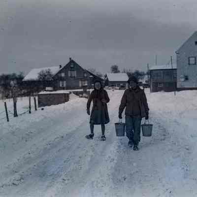Soldier carries water buckets for woman