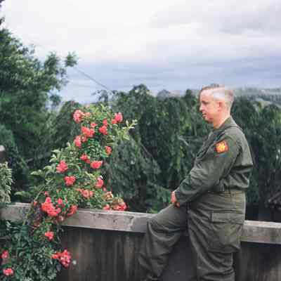 Chaplain sitting on ledge next to flowers