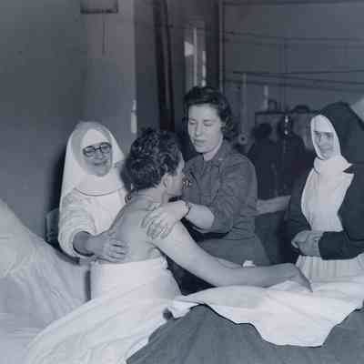Nurse and nuns care for wounded soldier