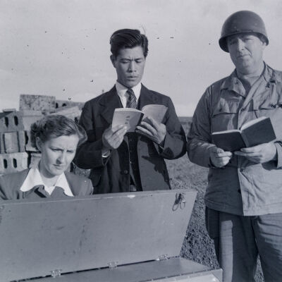 Soldier, Japanese man, and woman singing around a keyboard